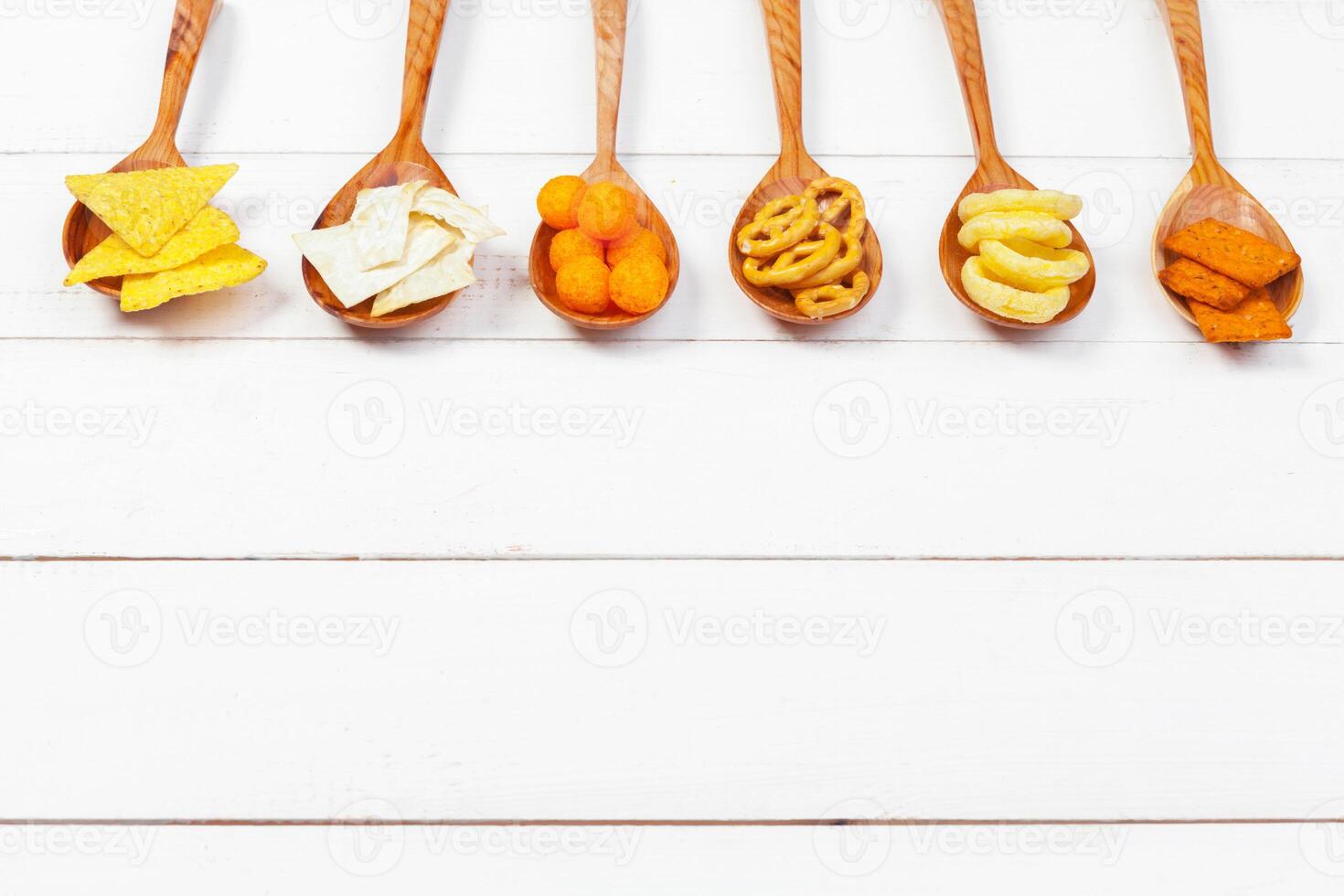 Mix of snacks . pretzels , crackers , chips and nachos on the table photo