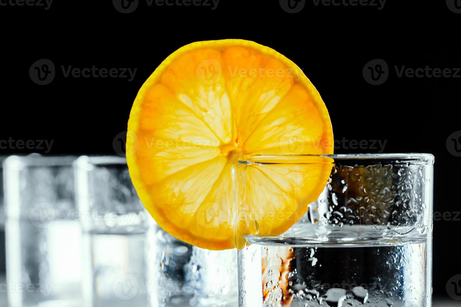 Cold vodka in shot glasses on a black background. photo