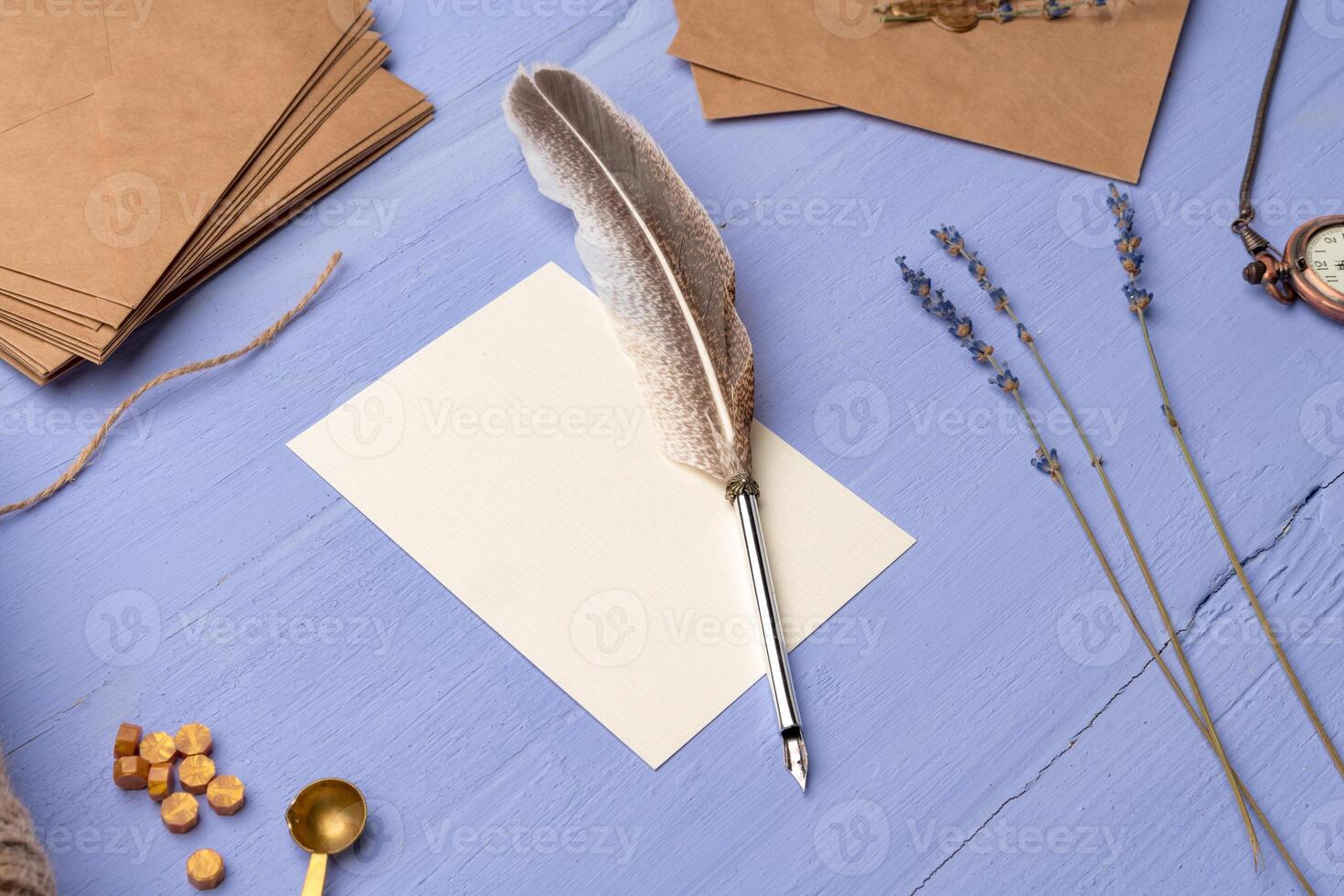 Blank paper with feather and envelopes on lavender wooden table photo