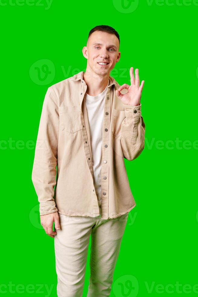 Man Smiling and Making Okay Gesture Against Bright Green Background photo