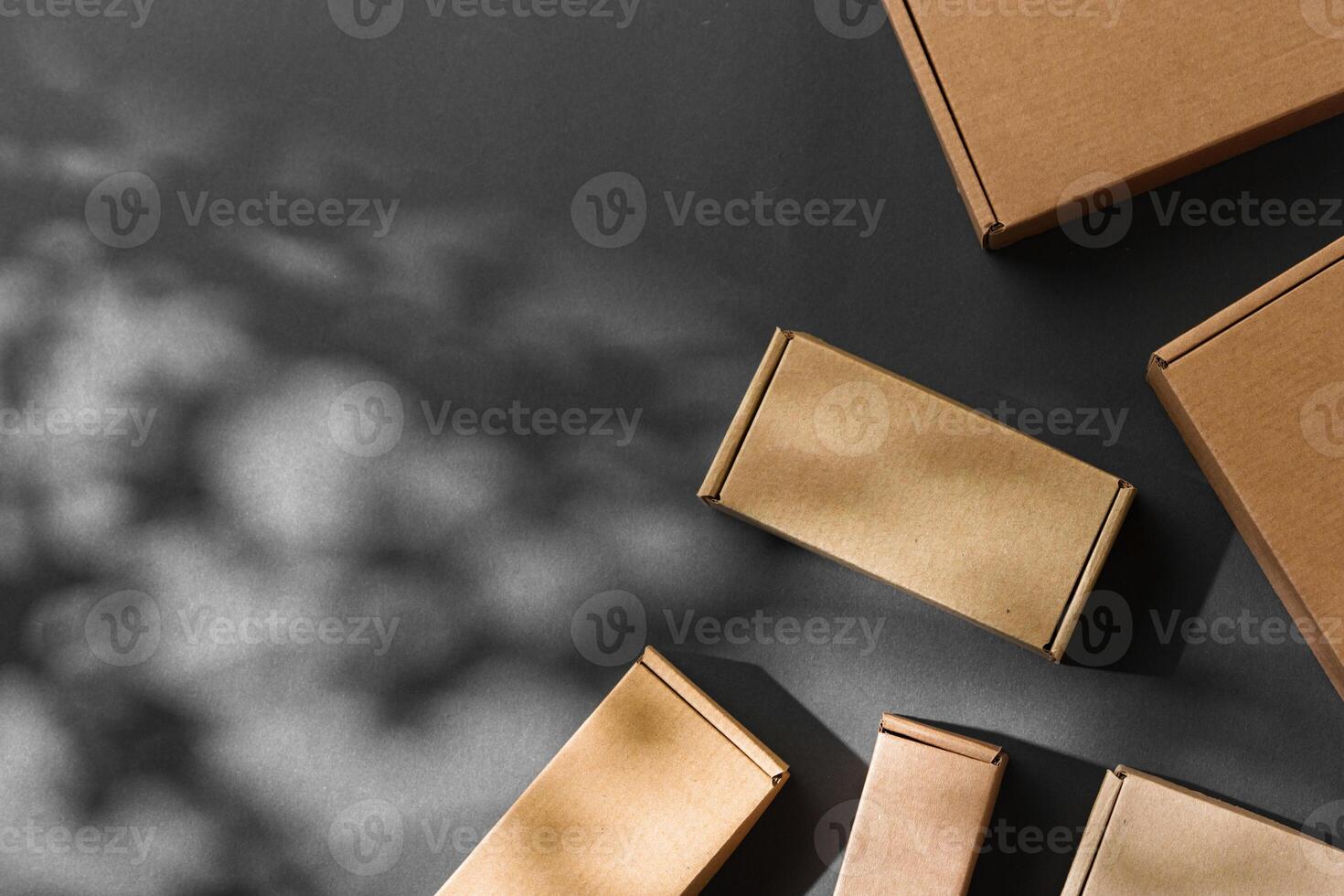 Various sizes of brown cardboard boxes arranged on a black surface with soft lighting effects during the day photo