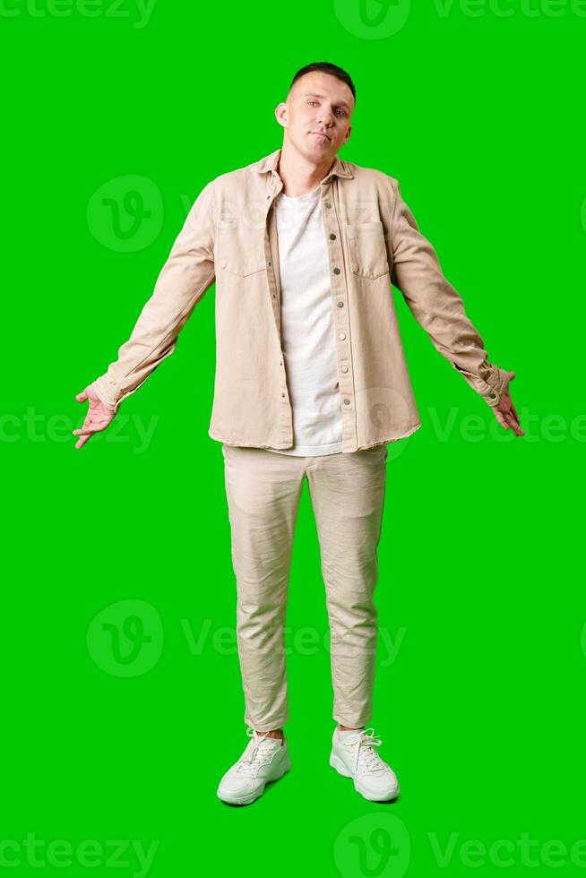 Young Man in Casual Outfit With Open Arms Posing Against Bright Green Background photo