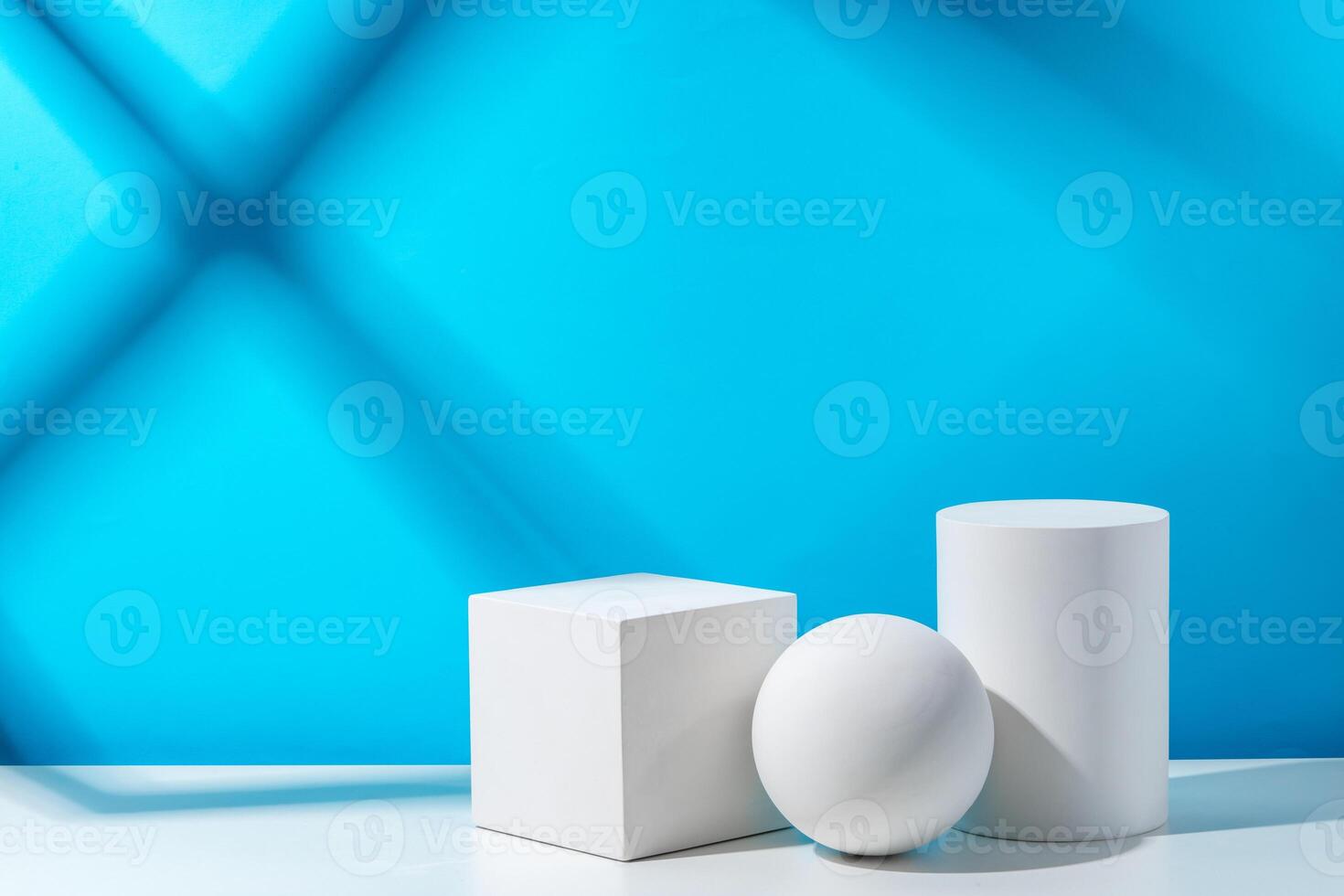 Three geometric shapes arranged on a table against a bright blue background during daytime lighting photo