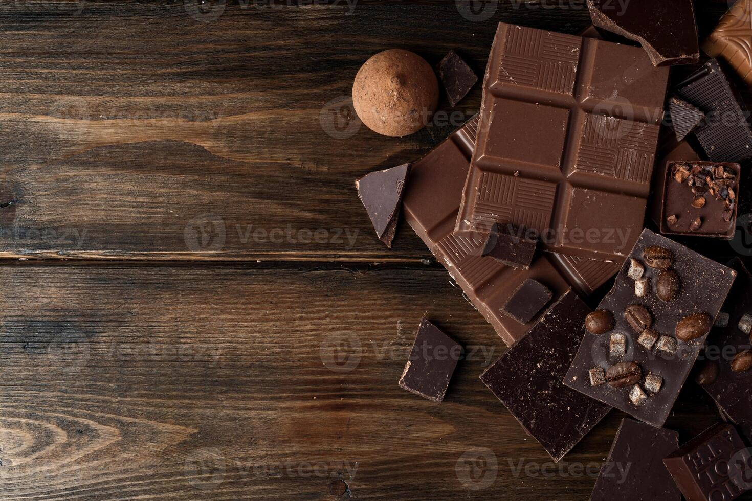 Broken chocolate bars on dark wooden background photo