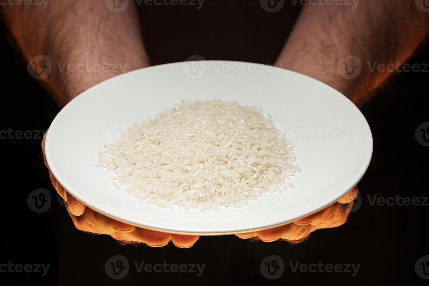 Hands holding a heap of dry rice grain on black background photo