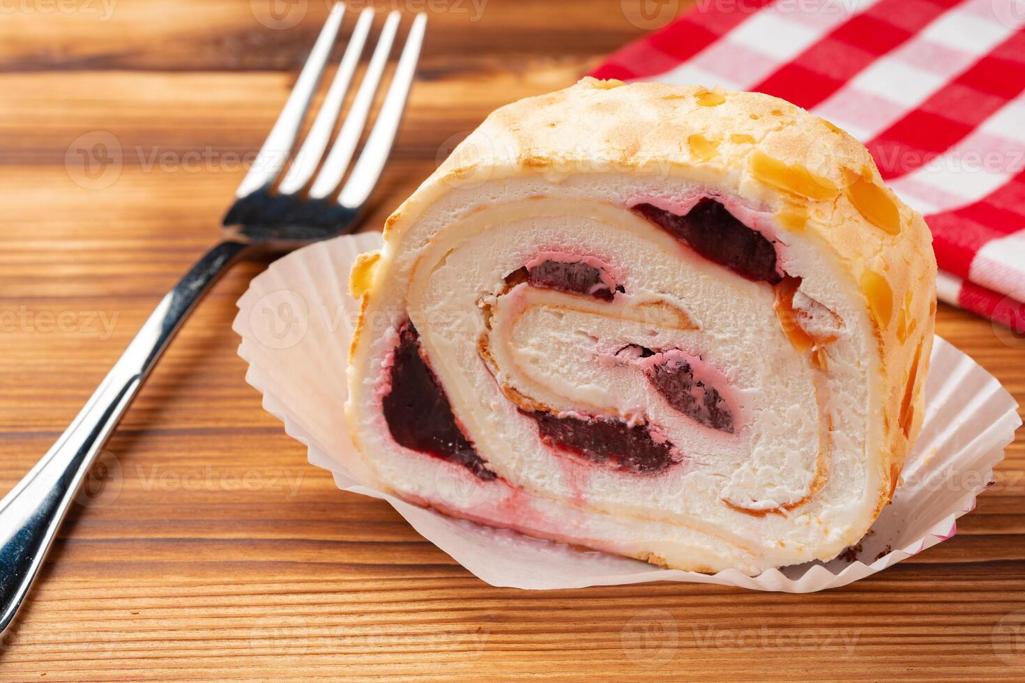 Meringue roll cake with cream on wooden table photo