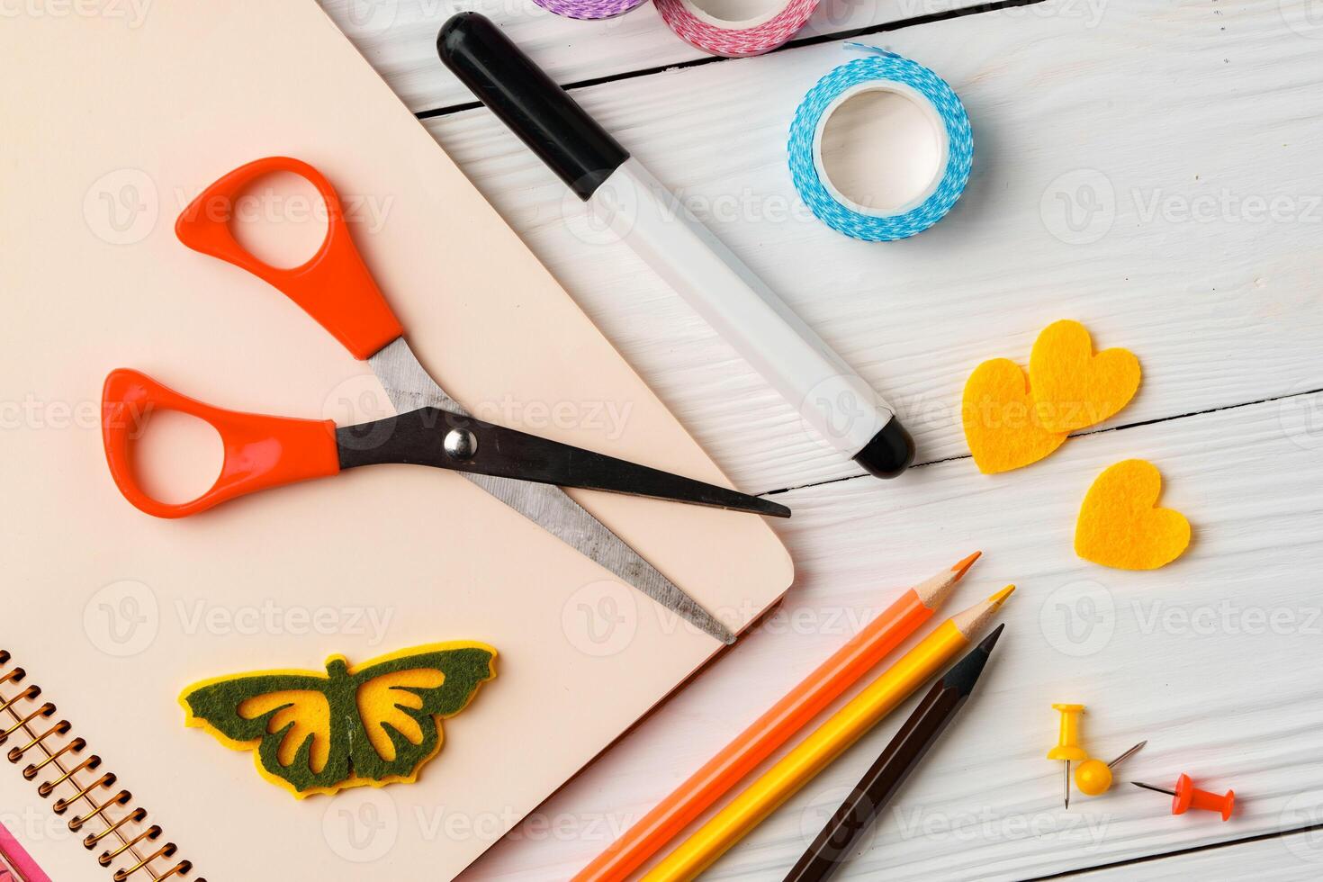 Colorful stationery arrangement with a butterfly sticker on a blank notebook at a wooden table in natural light photo