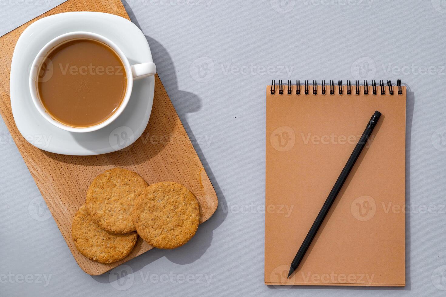 Cup of coffee with notebook on gray background top view photo