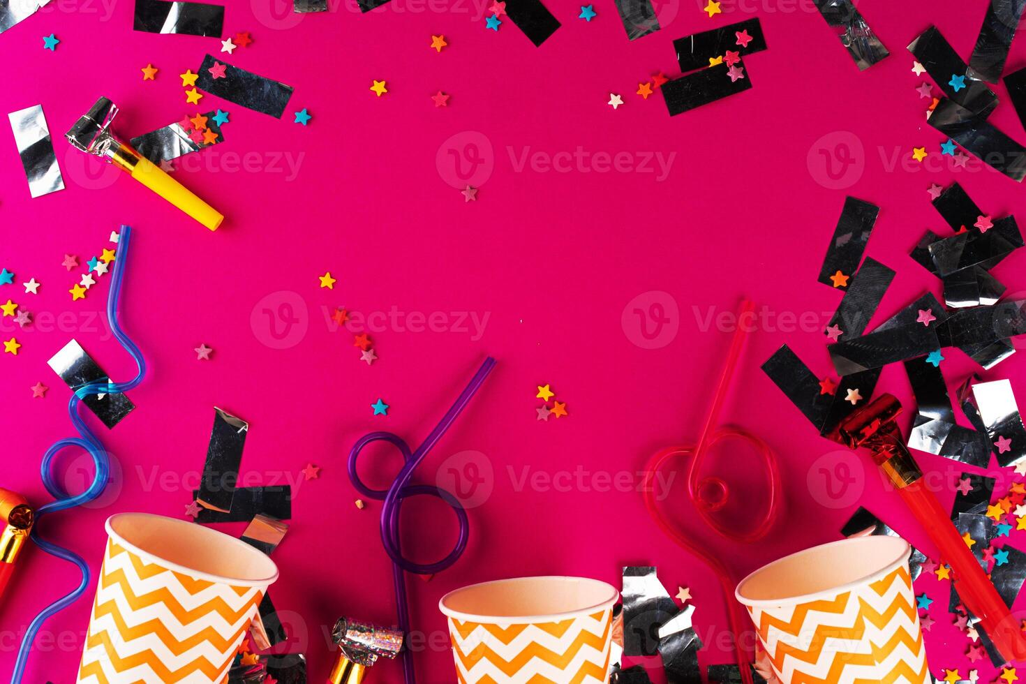 Party tinsel and colorful cups close up on purple background photo