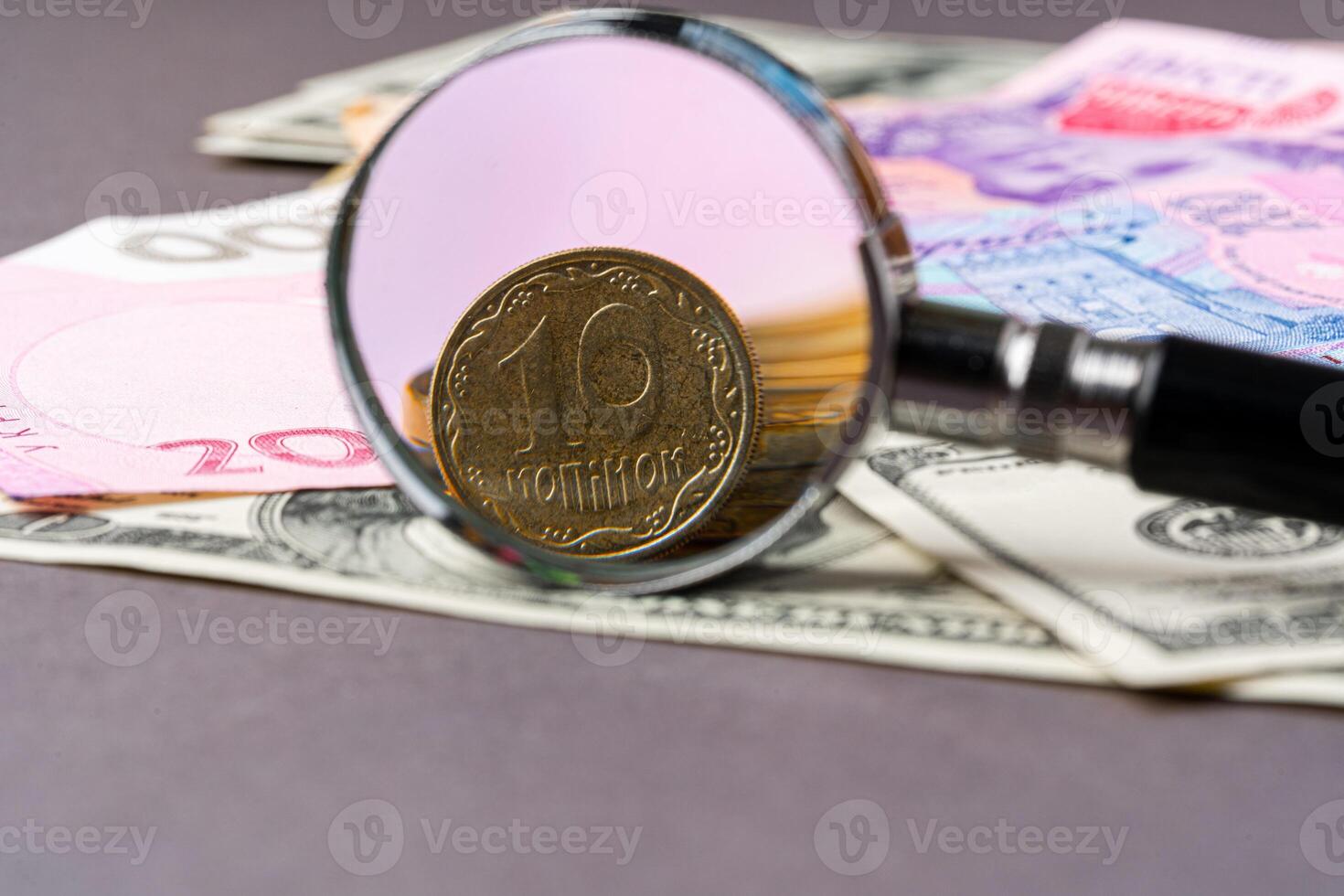 Magnifying glass on ukrainian hryvnia and Us dollars banknotes. Exchange rate concept photo