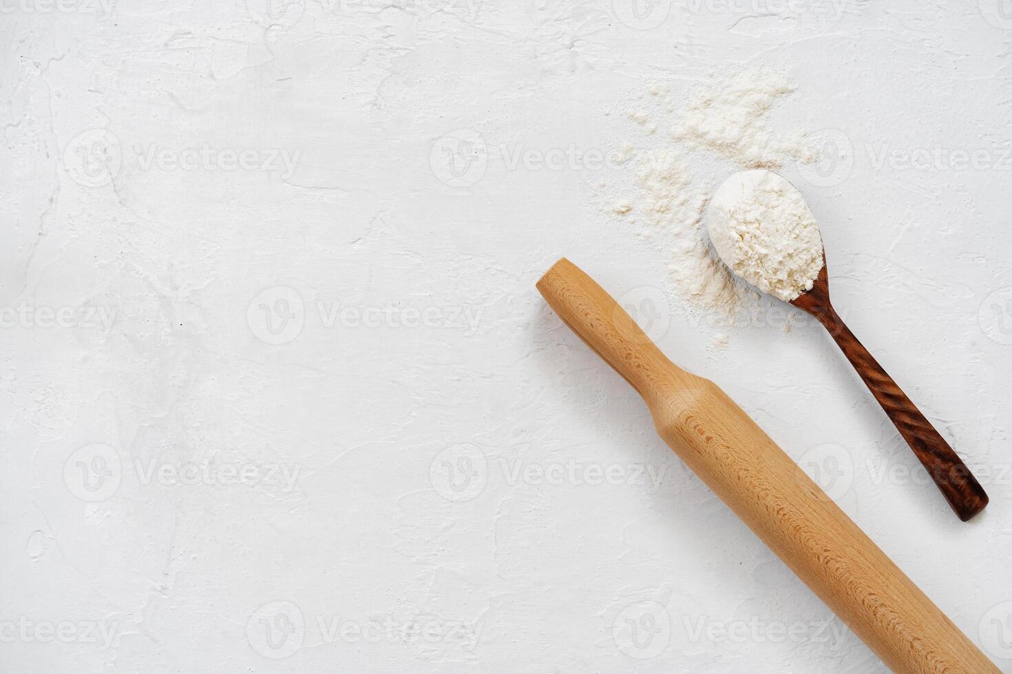 Pile of flour in wooden spoon on white background photo
