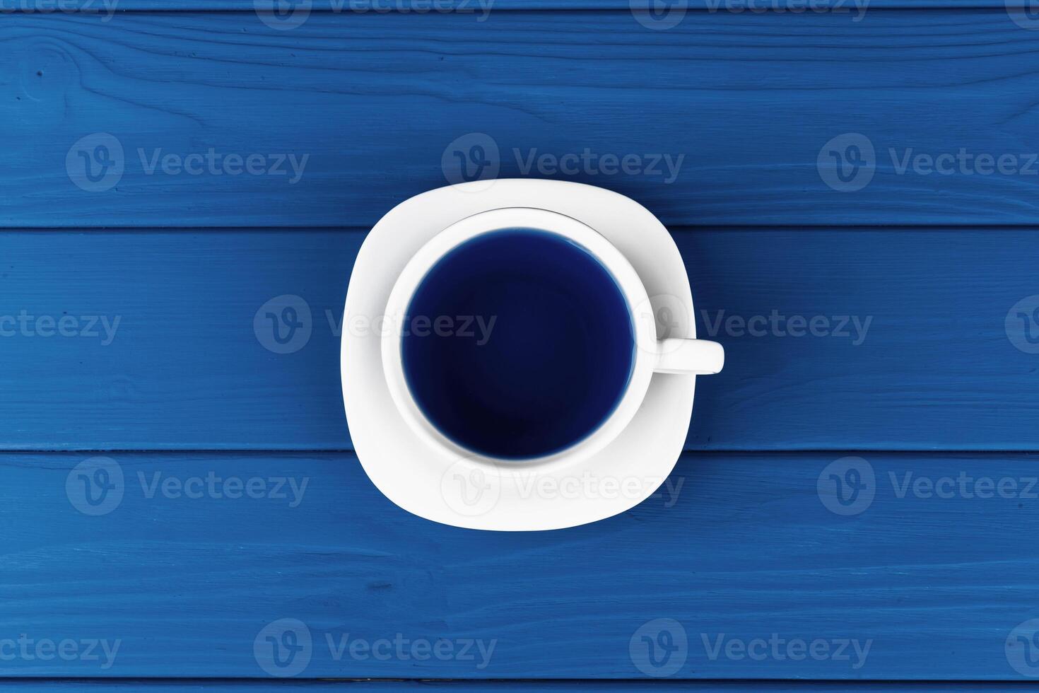 Top view of a cup of coffee on saucer on classic blue background photo