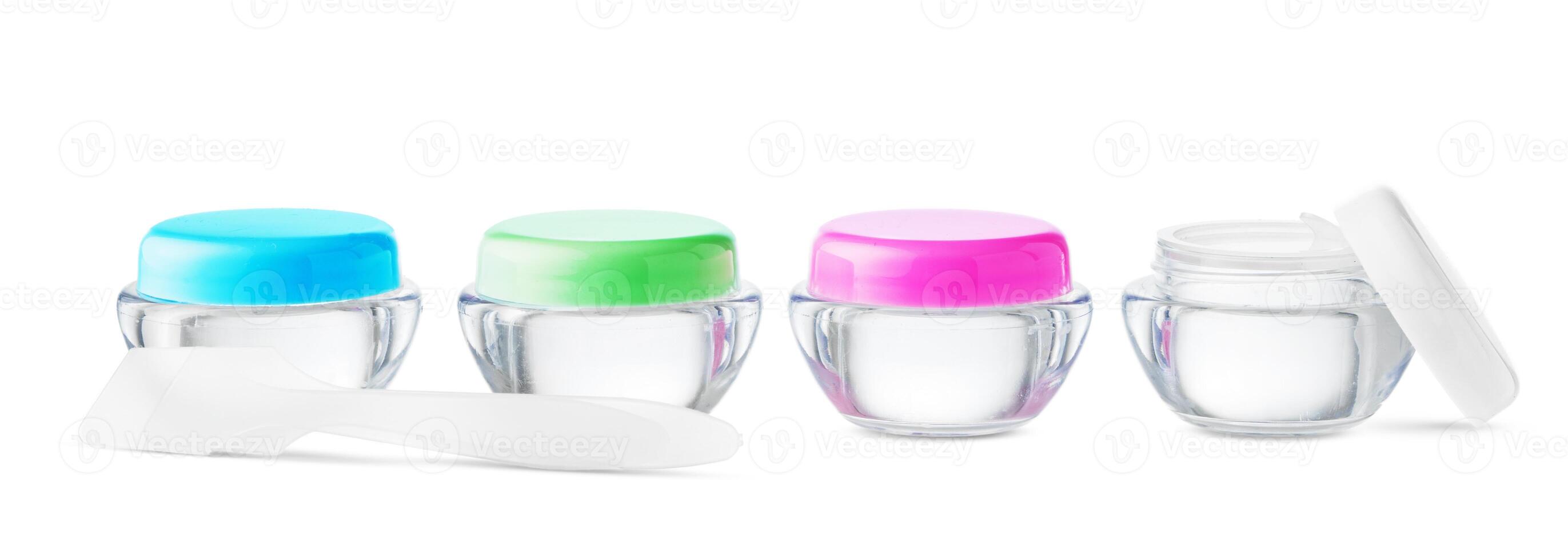 Clear cosmetic jars stacked with lids on a plain background photo