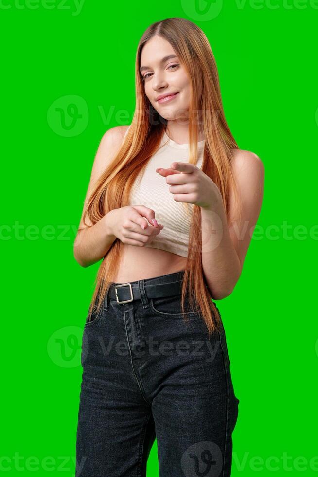 Smiling Young Woman Pointing at Camera With Green Screen Background photo