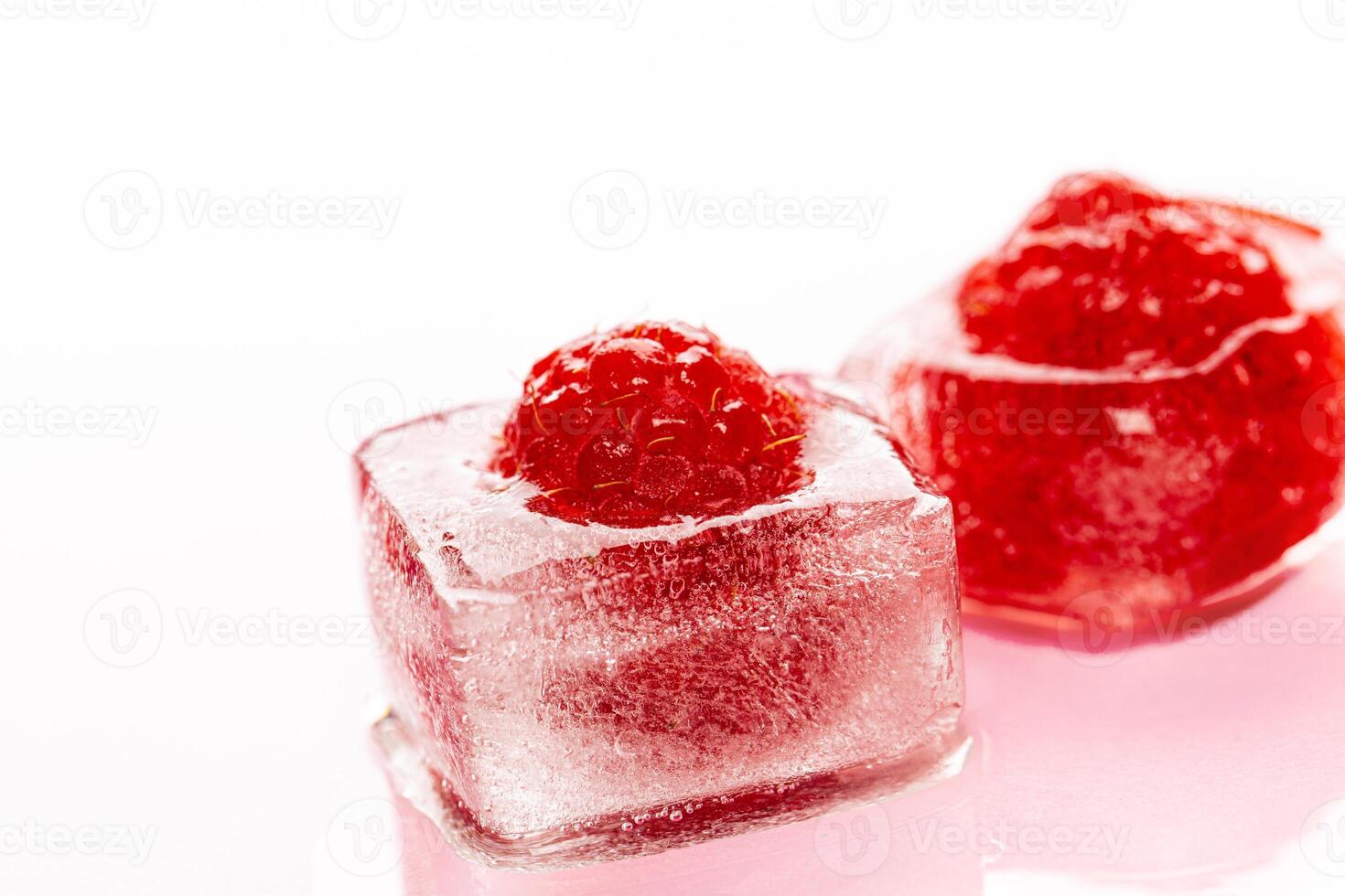 Raspberry ice cubes on pink glossy background photo
