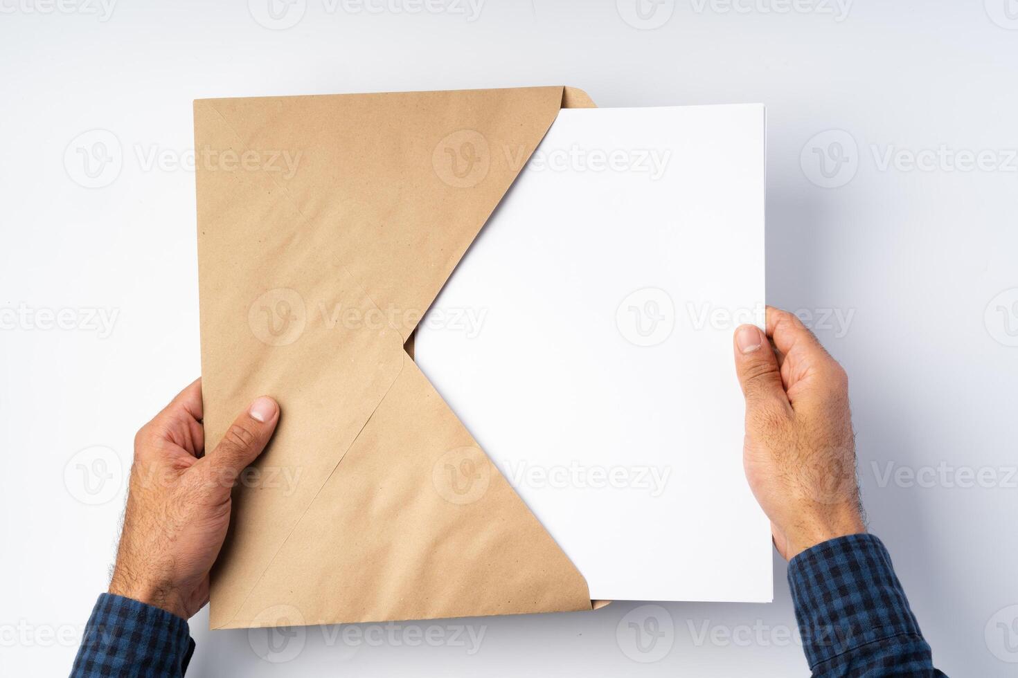 Male hands opening craft paper envelope above white surface photo