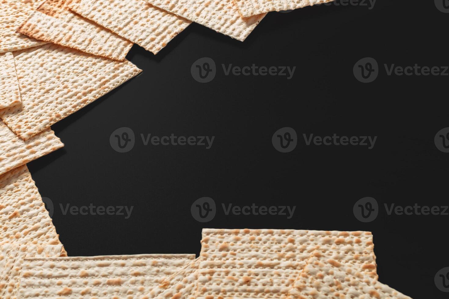 A photo of matzah or matza pieces on black background. Matzah for the Jewish Passover holidays. Place for text, copy space