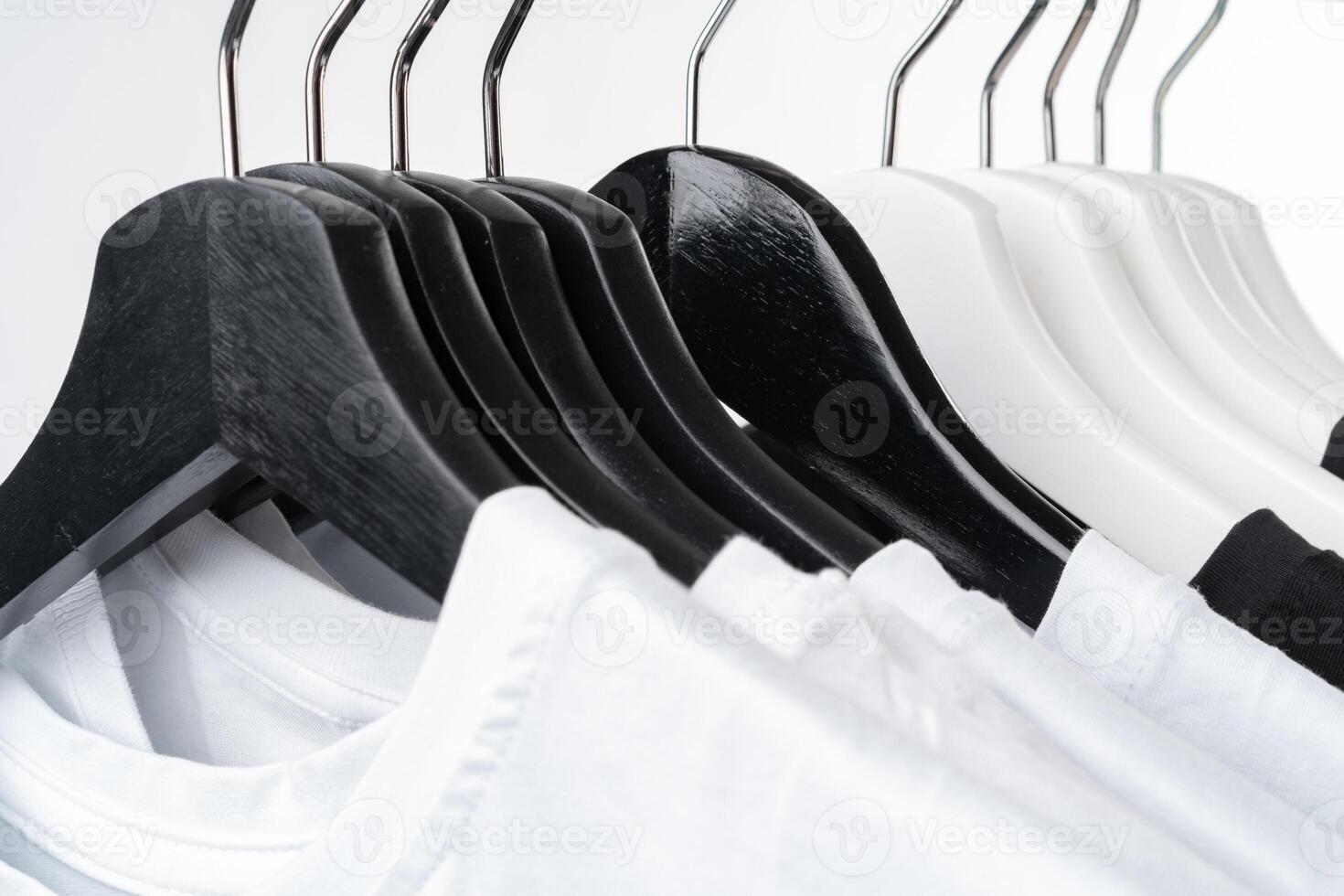 Black and white T-shirts on hangers on metal rack isolated on white photo
