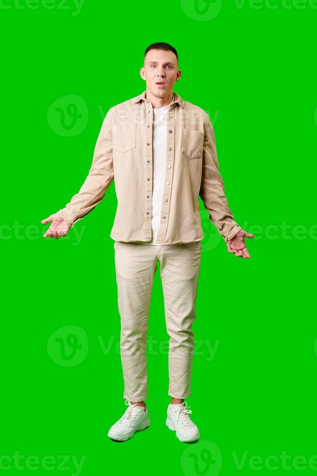 Confused Young Man Standing Against Bright Green Background With Open Arms in Uncertain Gesture photo