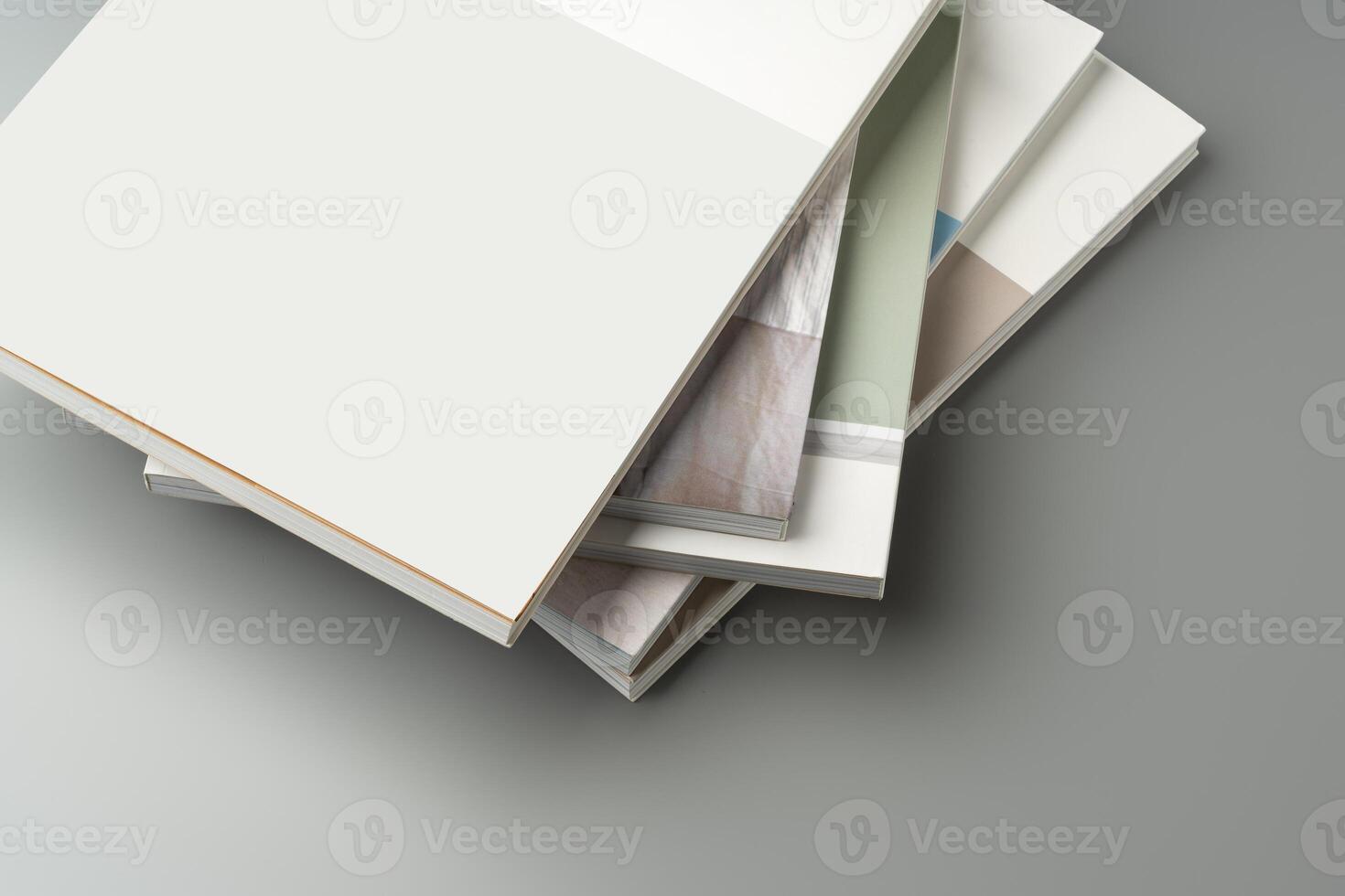 A stack of blank notebooks arranged neatly on a simple grey background photo