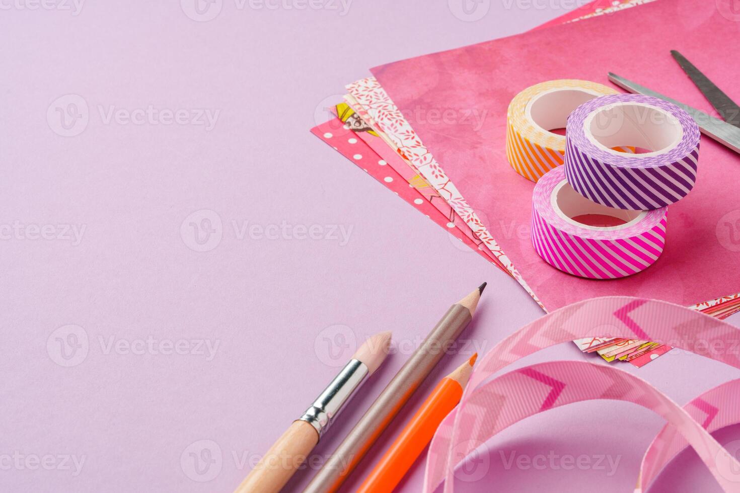 Scissors and decorative tape on colorful craft paper in a bright workspace photo