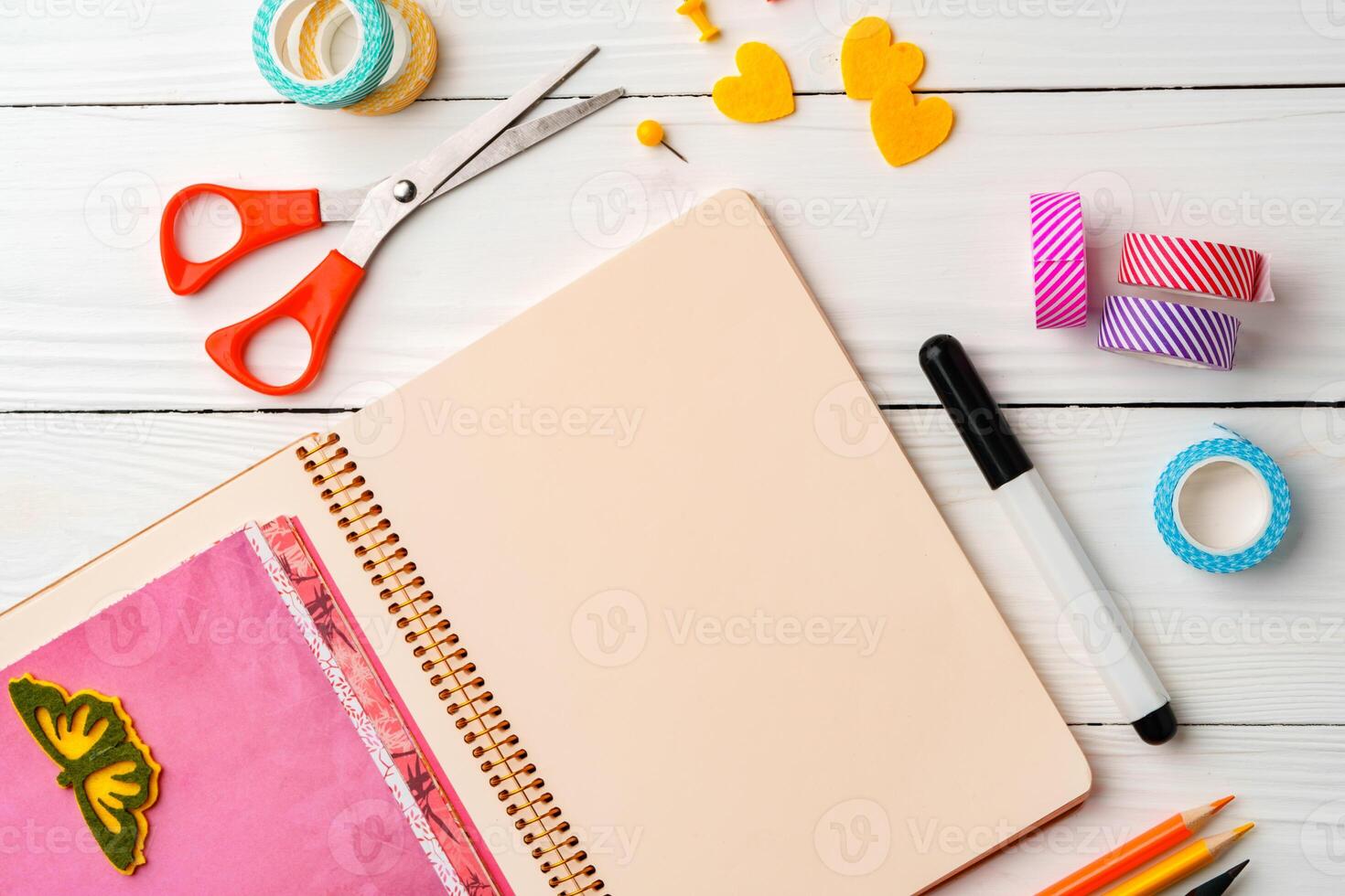 Creative workspace with open notebook, stationery, and decorative items on a wooden table photo