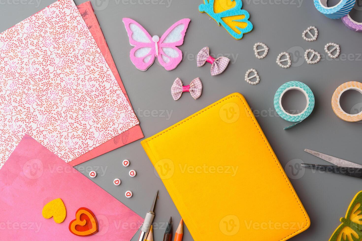 Crafting supplies arranged for a DIY project on a gray table with scissors, washi tape, and decorative items photo