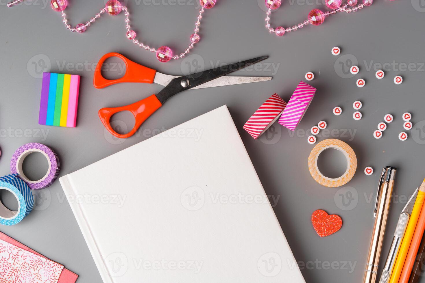 Crafting supplies arranged for a DIY project on a gray table with scissors, washi tape, and decorative items photo