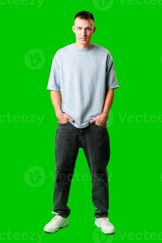 Young Man Standing Confidently Against Bright Green Background in Casual Attire photo