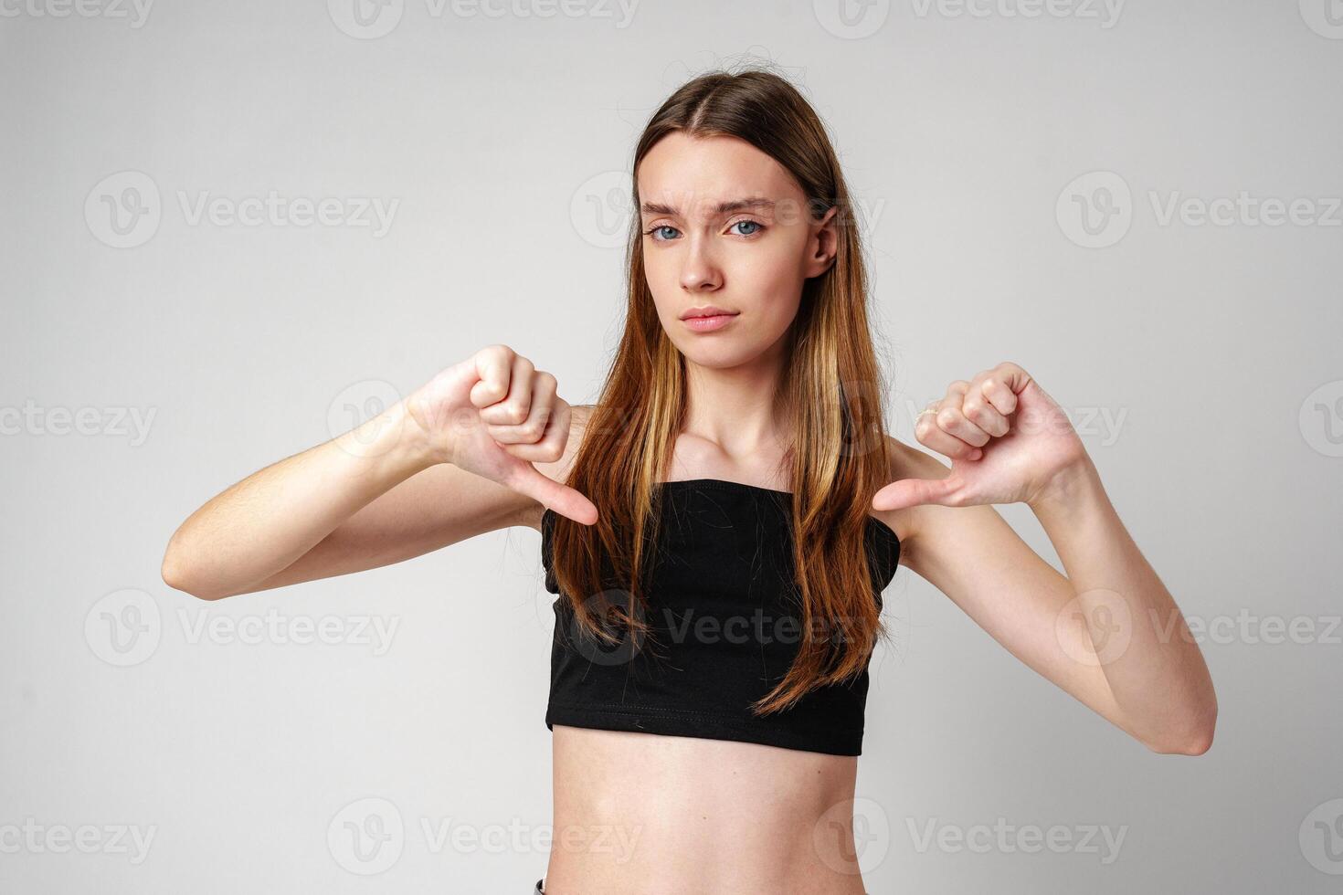Young Woman Pointing Downwards With Both Hands While Smiling photo