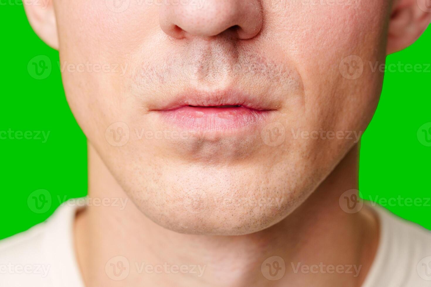 Close-Up of a Young Man's Face With Green Background Displaying Distinct Expression photo