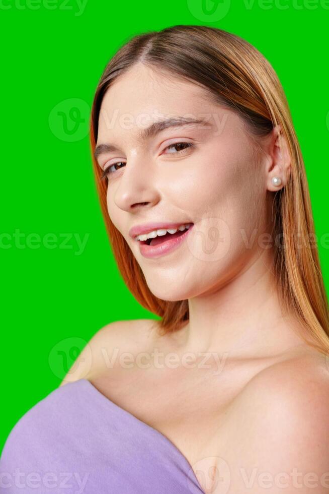 Young Woman With Long Brown Hair Smiles in a Purple Top Against Green Screen photo