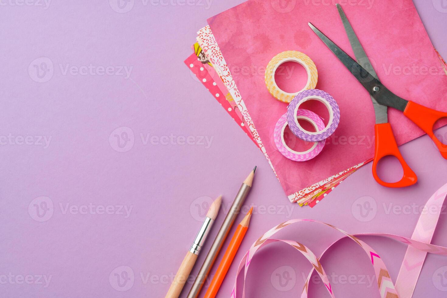 Scissors and decorative tape on colorful craft paper in a bright workspace photo