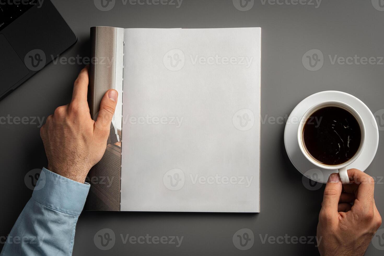Man Reading Page of Magazine While Holding Coffee Cup photo