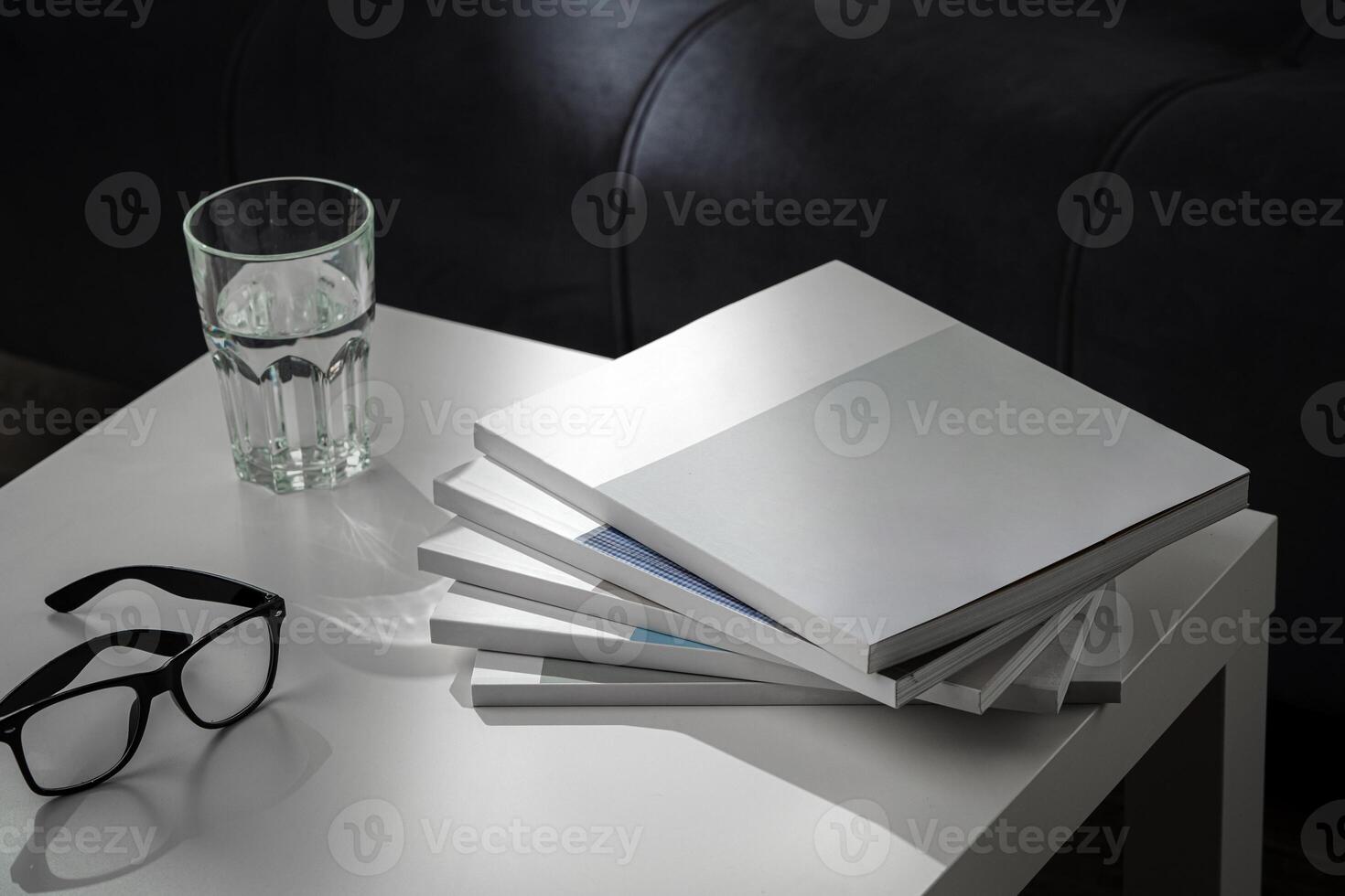 Eyeglasses with stack of books, and the glass of water on the table photo