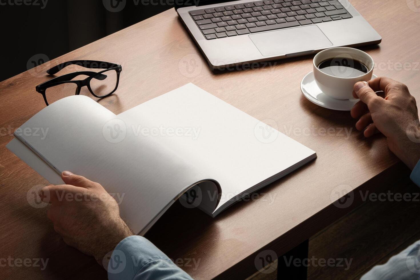 Man Reading Page of Magazine While Holding Coffee Cup photo