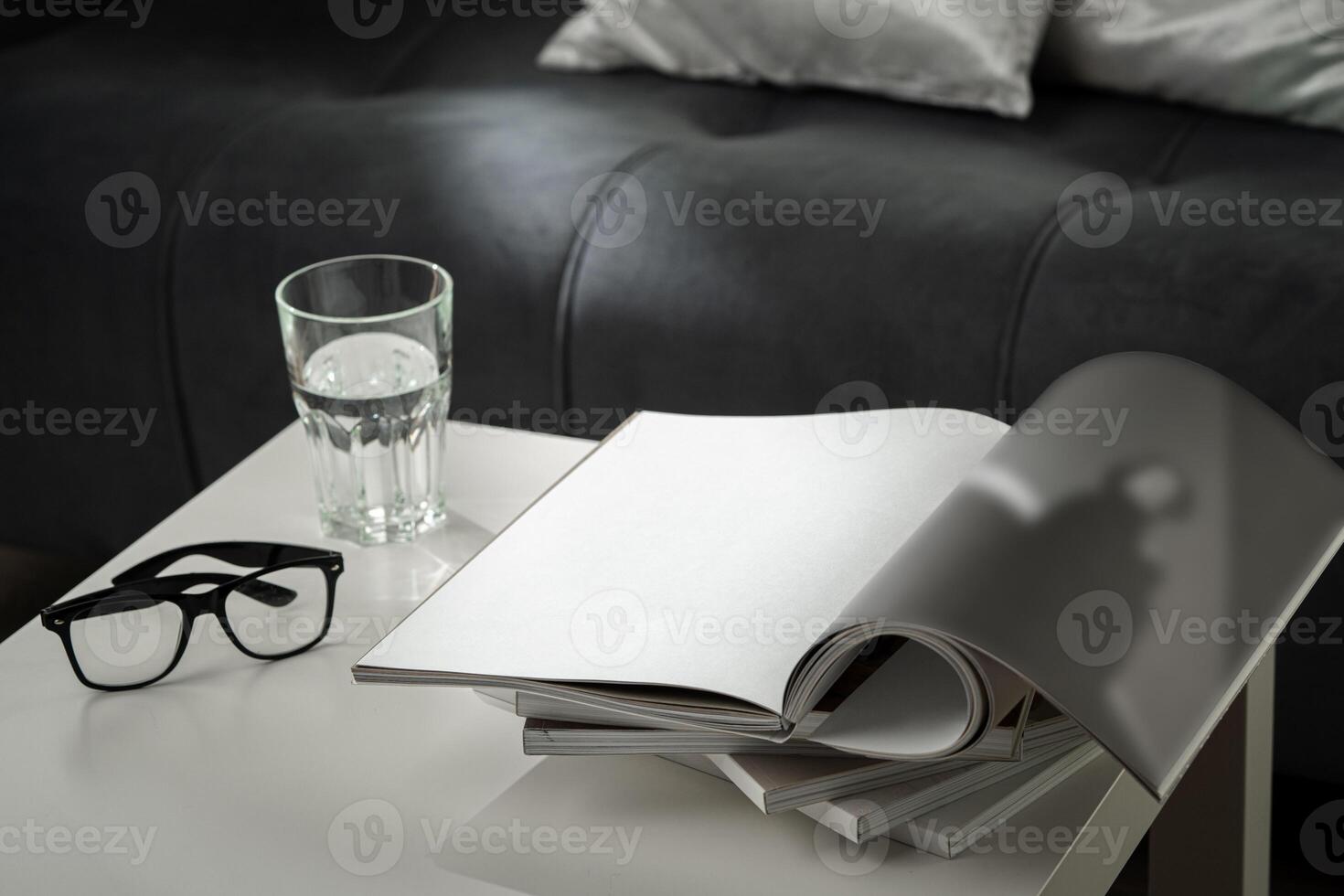 Eyeglasses with stack of books, and the glass of water on the table photo