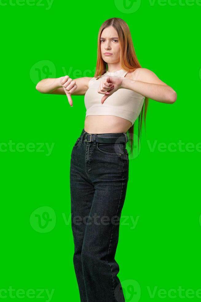 Young Woman Giving Thumbs Down In Front Of Green Screen photo