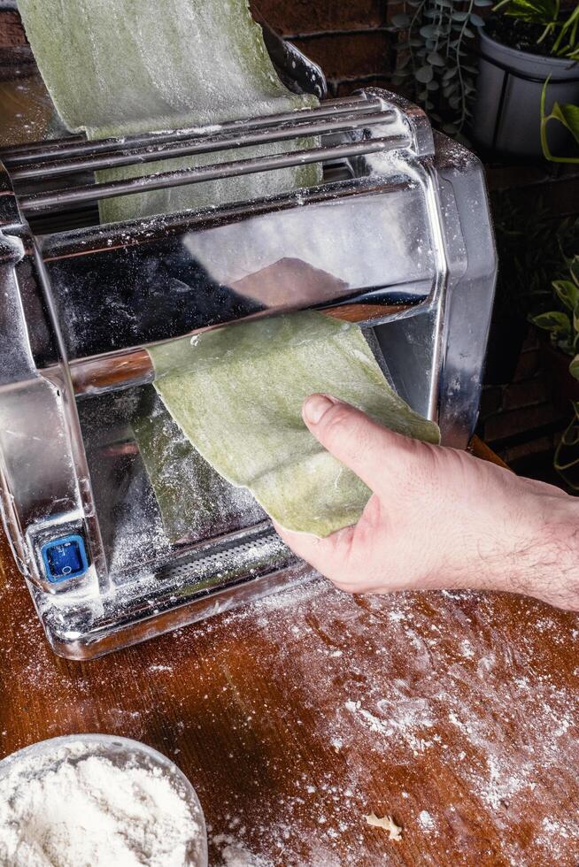Man rolling out pasta to make spinach ravioli. photo
