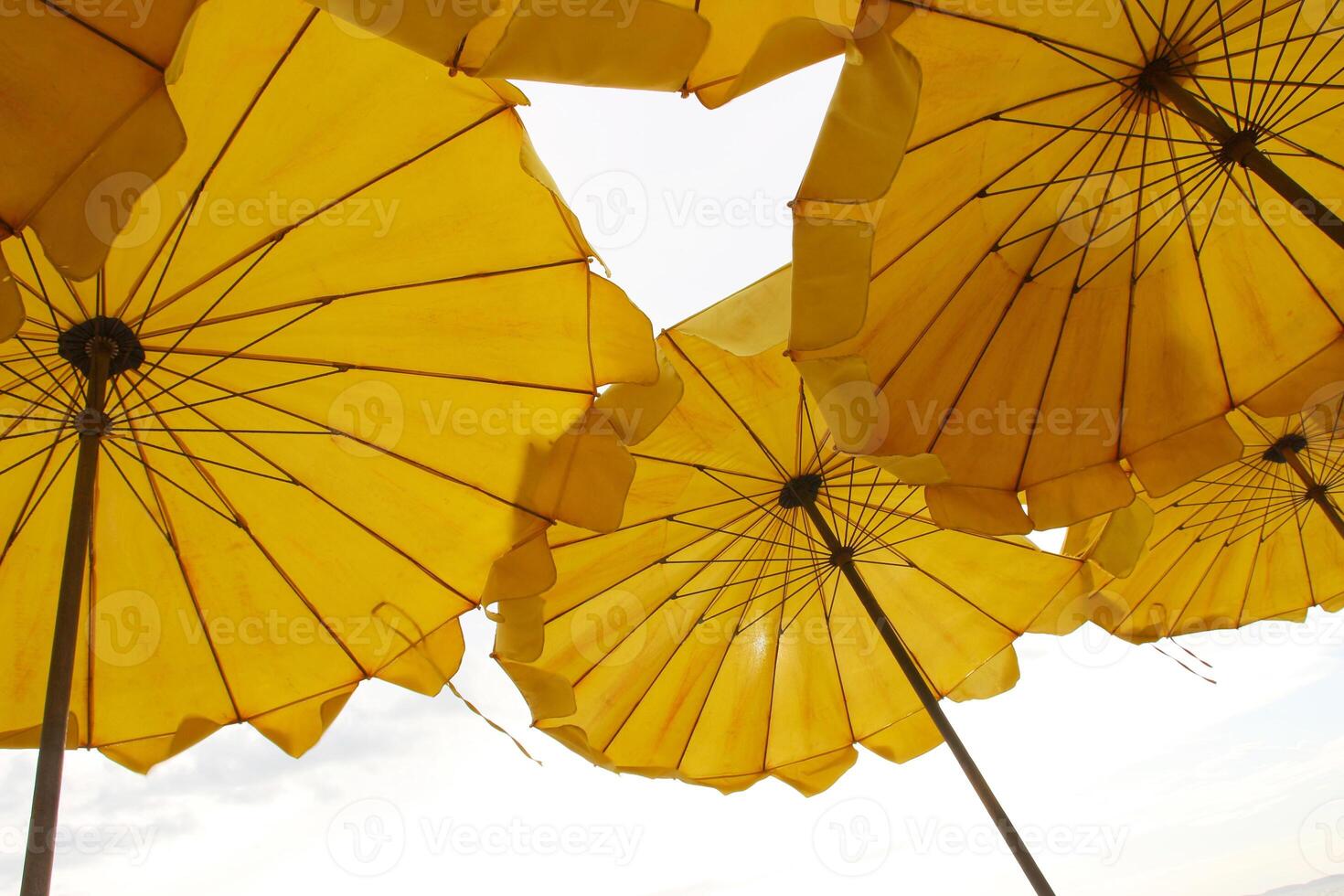 Yellow beach umbrella on blue sky and white clouds photo