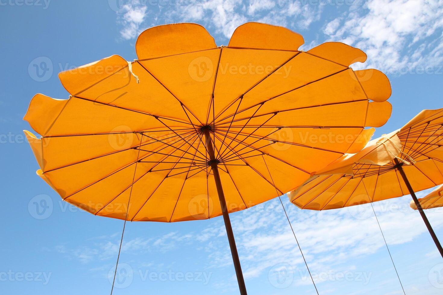 Yellow beach umbrella on blue sky and white clouds photo