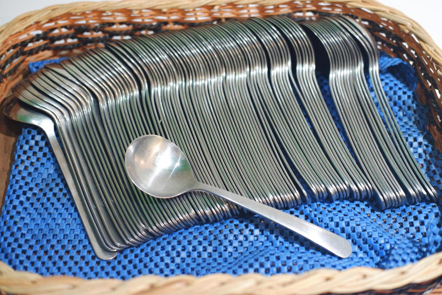 Stainless steel spoon in a wicker basket on a blue background photo