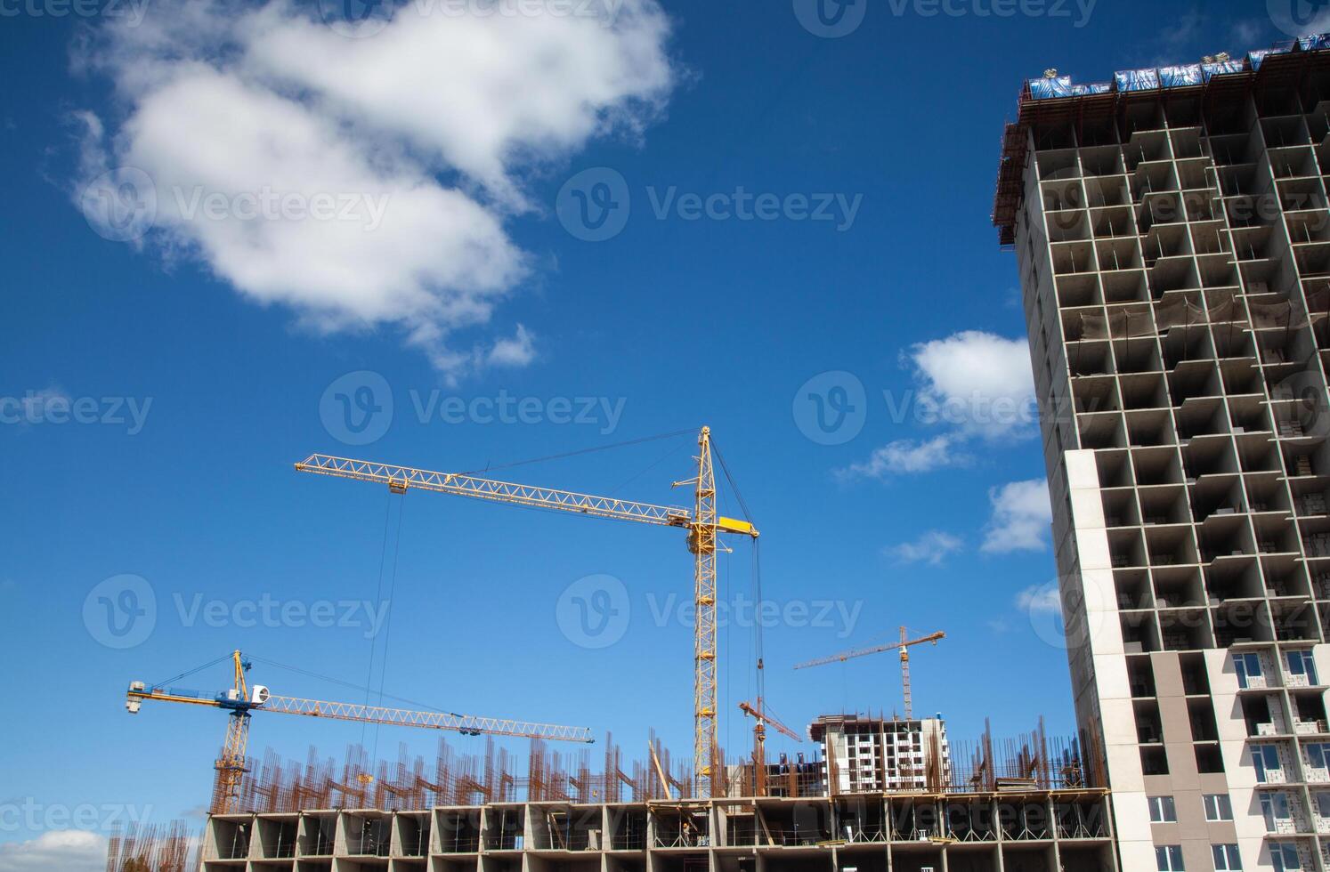 Construction site with multiple tall cranes working on building a high-rise structure under a clear blue sky photo