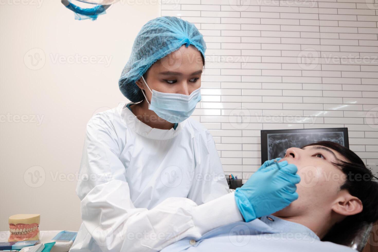 Asian female dentist examine young male patient teeth and toothache stomatology in dental clinic, well-being hygiene checks, and professional orthodontic healthcare work in doctor's office hospital. photo