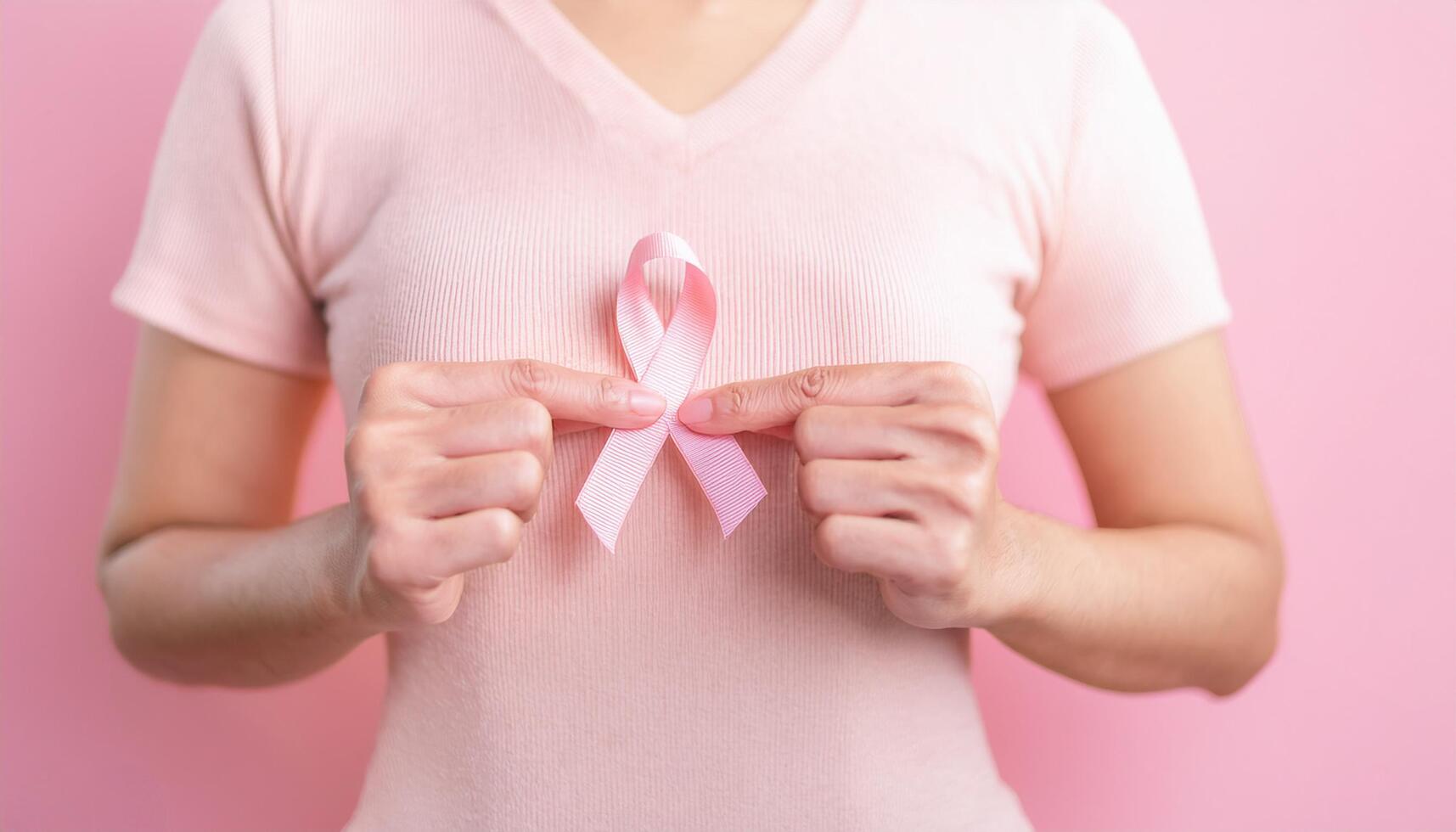 Women holding pink ribbon with both hands, breast cancer awareness concept photo