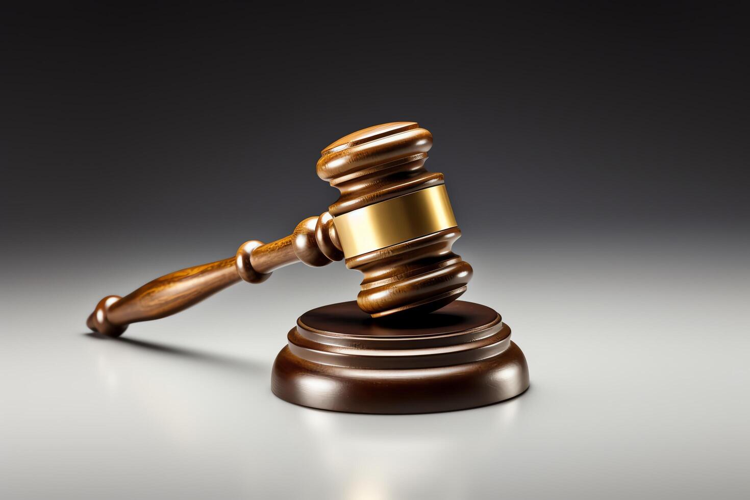 A wooden judge's gavel resting on a sound block. The gavel has a gold band around the middle. photo