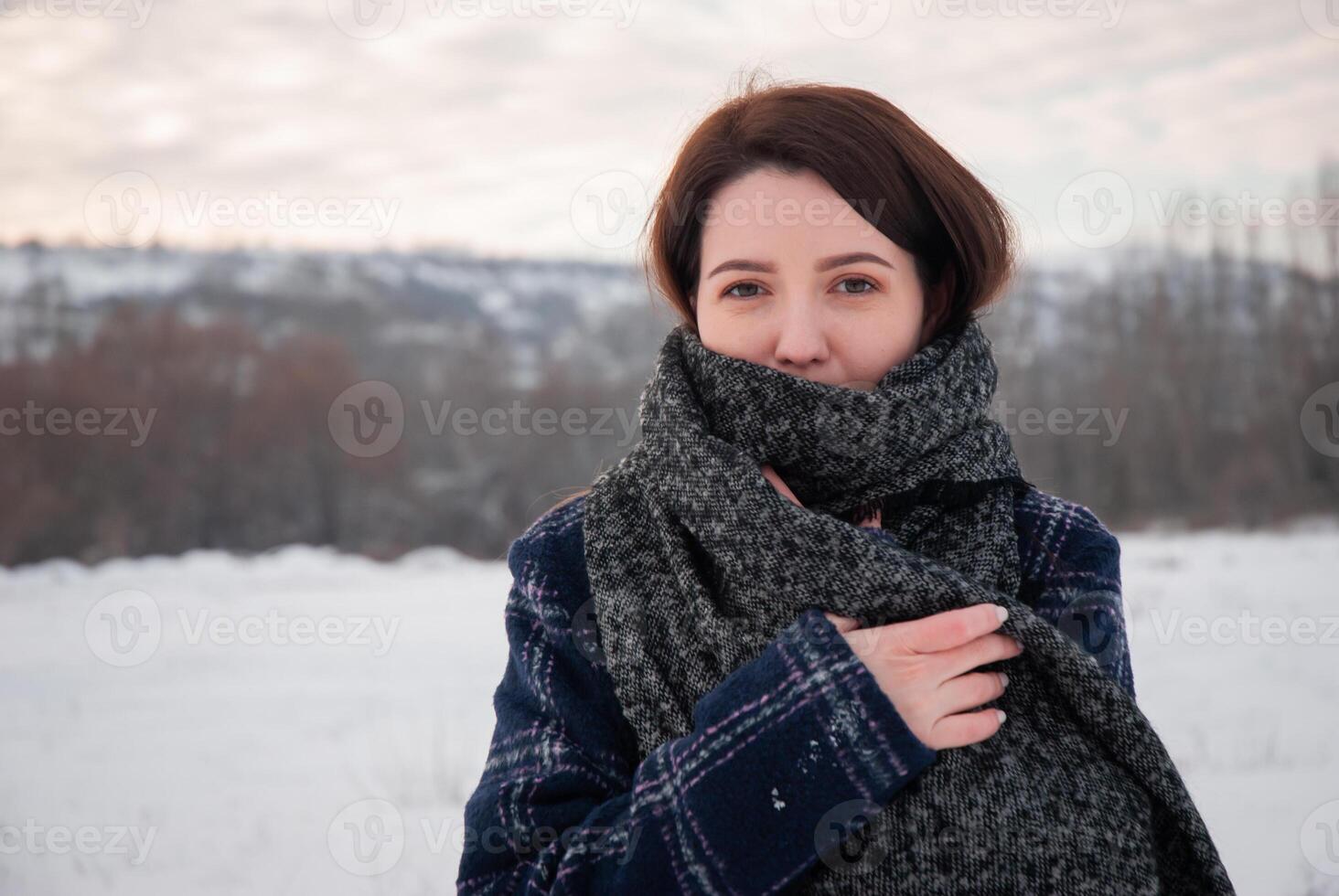 A woman in a plaid coat and thick scarf standing in a snowy field, with a serene and confident expression, representing winter elegance and warmth. Captures comfort and seasonal style photo