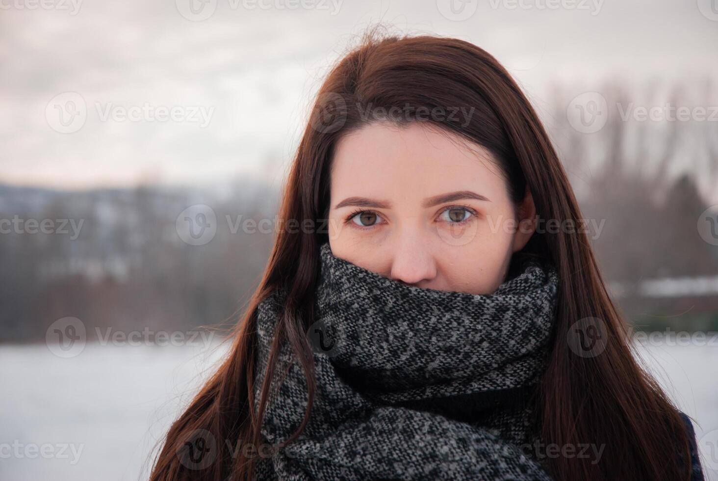 A woman in a grey scarf gazing into the distance in a winter landscape, showcasing serene beauty and calm in the cold season photo