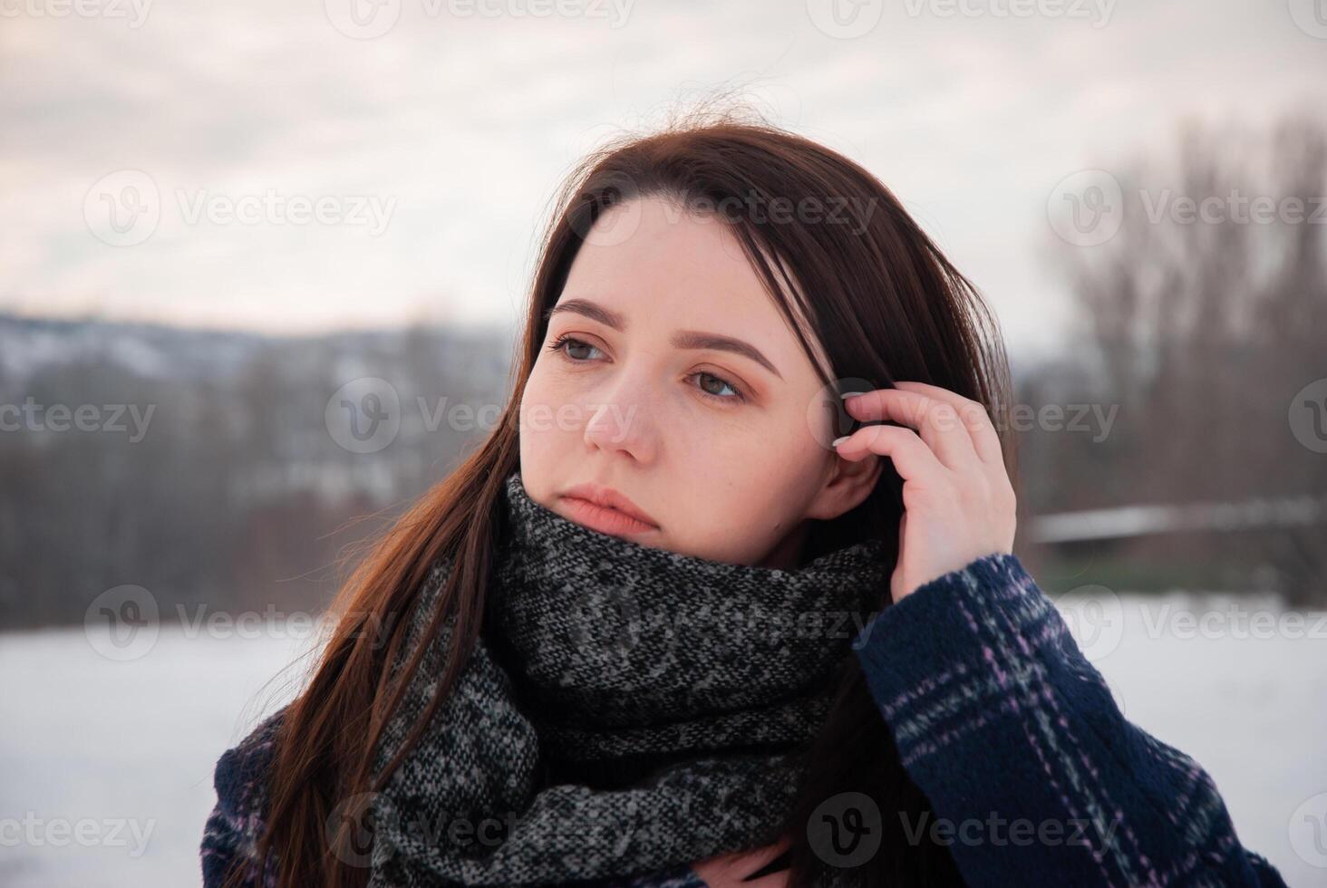 A close-up of a woman wearing a grey scarf and blue coat in a snowy outdoor setting, conveying a feeling of warmth and peacefulness in winter photo