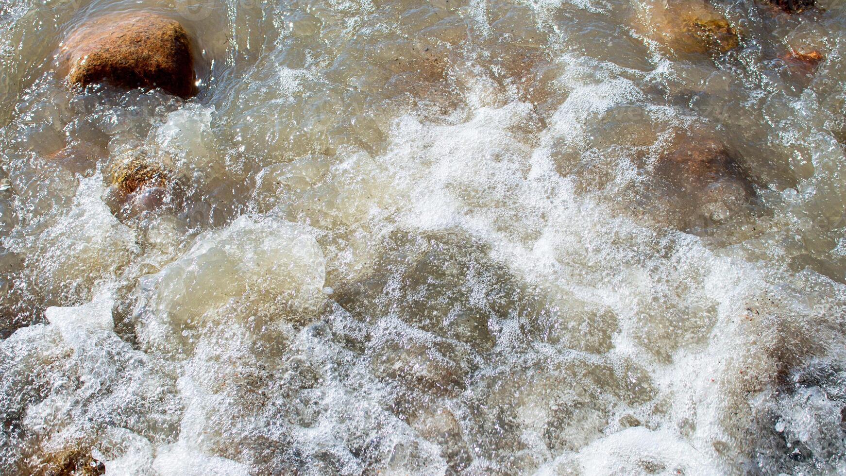 Wild sea, ocean with splashes on stones. Wave rolls onto shore. Top view, drone. Nature photo